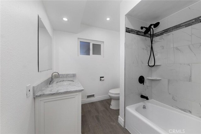 full bathroom featuring toilet, tiled shower / bath combo, vanity, and hardwood / wood-style floors