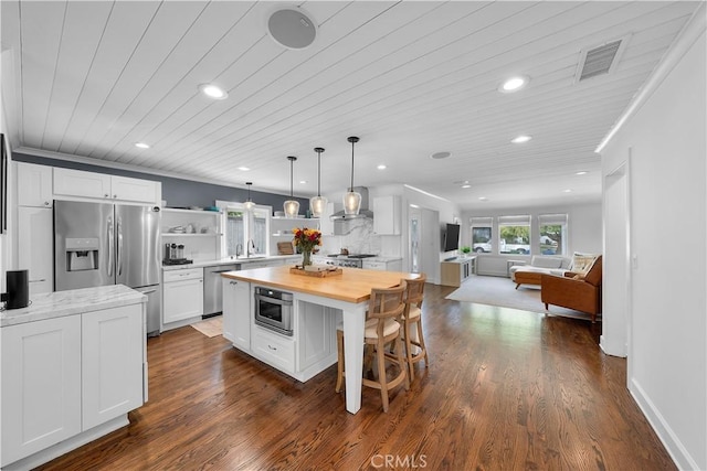 kitchen with white cabinets, wooden ceiling, wall chimney exhaust hood, pendant lighting, and appliances with stainless steel finishes