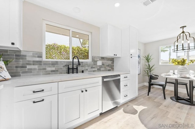 kitchen featuring dishwasher, light stone counters, sink, white cabinetry, and backsplash