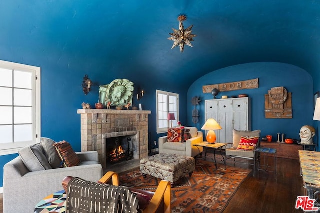 living room with a brick fireplace, hardwood / wood-style floors, and vaulted ceiling