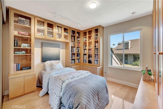 bedroom featuring rail lighting and light hardwood / wood-style floors