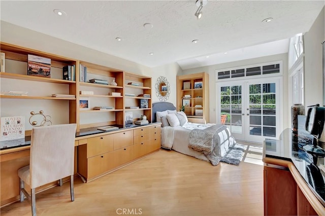 bedroom with built in desk, french doors, light wood-type flooring, and access to exterior