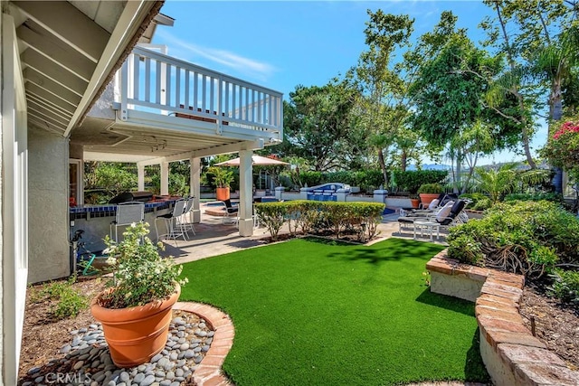 view of yard featuring exterior bar, a balcony, area for grilling, and a patio