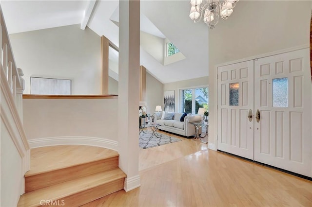 foyer featuring wood-type flooring, high vaulted ceiling, an inviting chandelier, and beamed ceiling