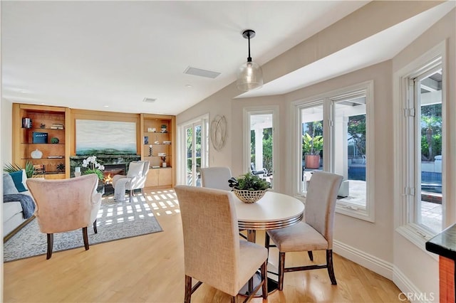 dining area with light wood-type flooring and built in features