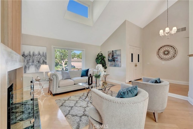 living room with a premium fireplace, high vaulted ceiling, a notable chandelier, and light hardwood / wood-style floors