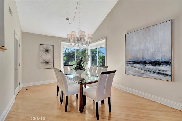 dining room with light hardwood / wood-style floors, vaulted ceiling, and a chandelier