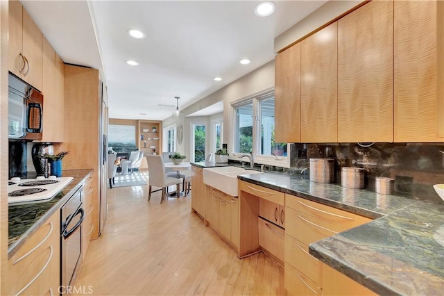 kitchen featuring light hardwood / wood-style flooring, light brown cabinets, decorative backsplash, white cooktop, and sink