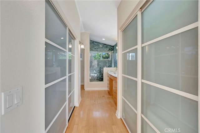 hallway with lofted ceiling and light hardwood / wood-style flooring