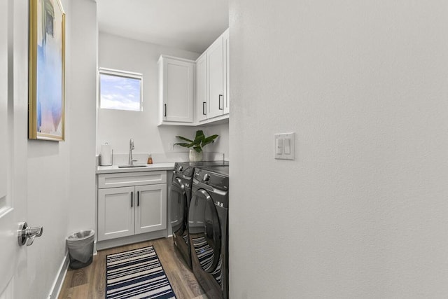 laundry room featuring dark wood-type flooring, cabinets, washing machine and clothes dryer, and sink