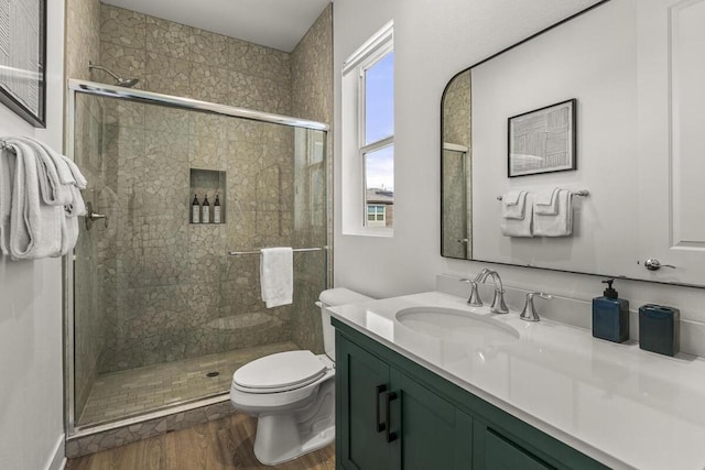 bathroom with toilet, a shower with door, vanity, and hardwood / wood-style floors