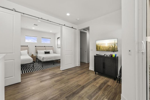 bedroom featuring a barn door and dark hardwood / wood-style floors