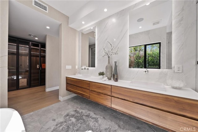 bathroom featuring vanity, a washtub, and hardwood / wood-style flooring