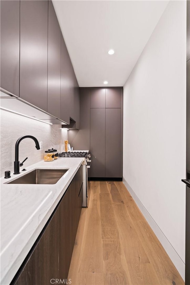 kitchen featuring light hardwood / wood-style flooring, sink, dark brown cabinets, and gas stove