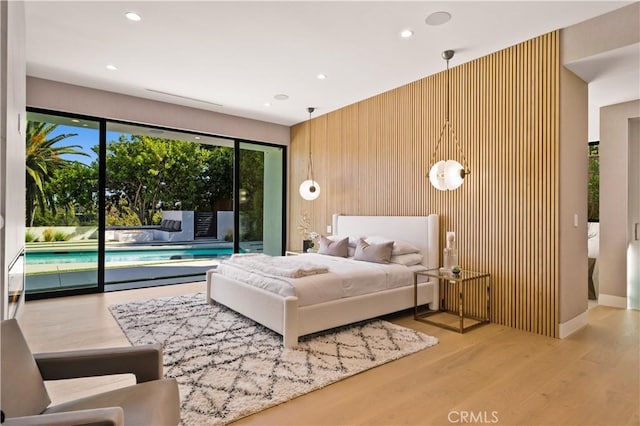 bedroom featuring access to outside, wooden walls, and light hardwood / wood-style flooring