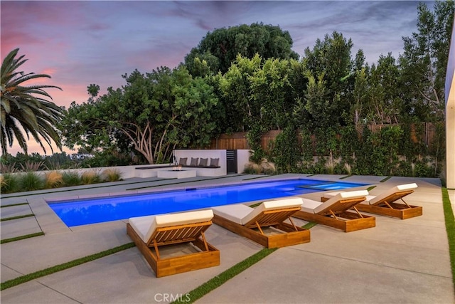 pool at dusk featuring a patio