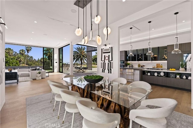 dining area featuring hardwood / wood-style flooring, floor to ceiling windows, sink, and a wealth of natural light