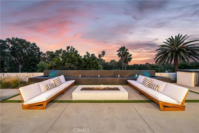 patio terrace at dusk with an outdoor living space with a fire pit