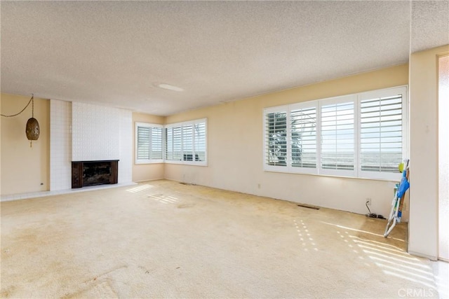 unfurnished living room with carpet flooring, a textured ceiling, and a large fireplace