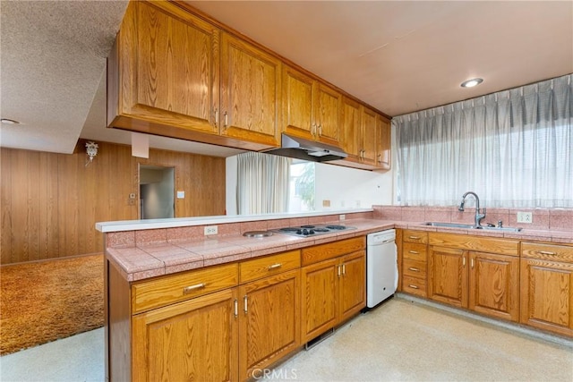 kitchen with a sink, a peninsula, brown cabinets, and dishwasher