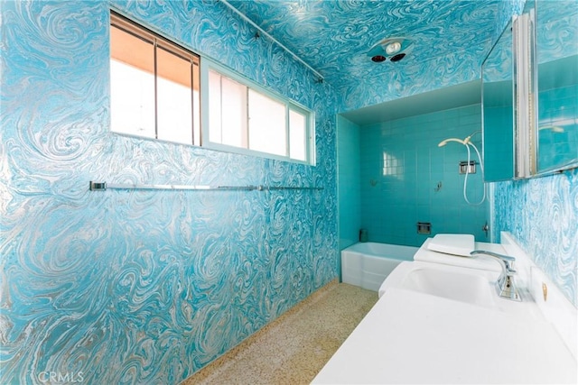 bathroom with a sink, walk in shower, and wallpapered walls