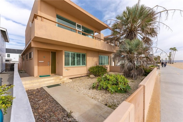 exterior space with stucco siding, fence, and a balcony