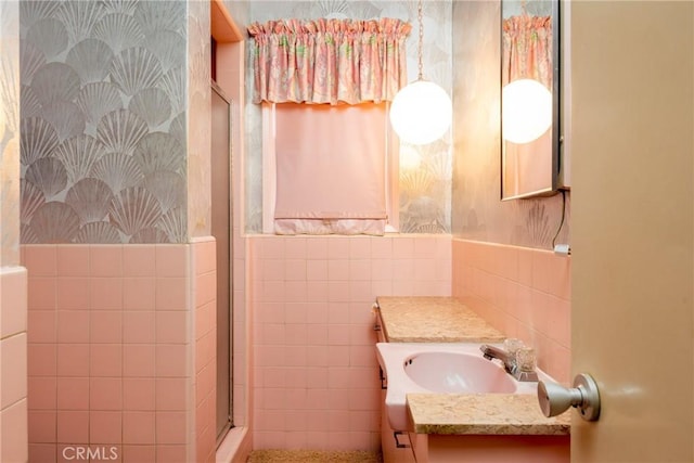bathroom with a wainscoted wall, vanity, tile walls, and a shower stall