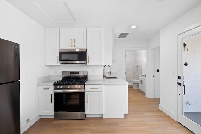 kitchen featuring appliances with stainless steel finishes, light hardwood / wood-style floors, white cabinetry, and sink