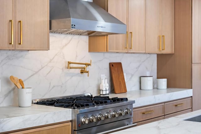 kitchen with wall chimney range hood, light brown cabinetry, backsplash, and high end stove