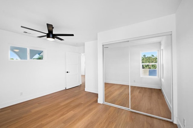 unfurnished bedroom with ceiling fan, light wood-type flooring, and a closet