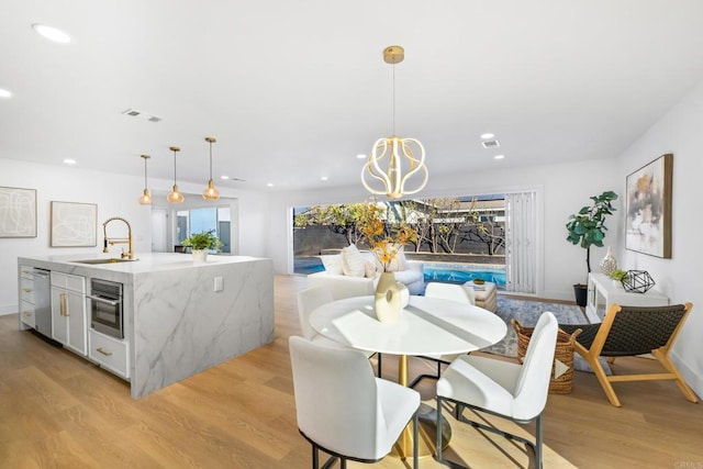 dining area featuring an inviting chandelier, light wood-type flooring, and sink