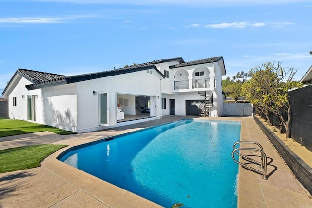 back of property featuring a patio area, a balcony, and a fenced in pool