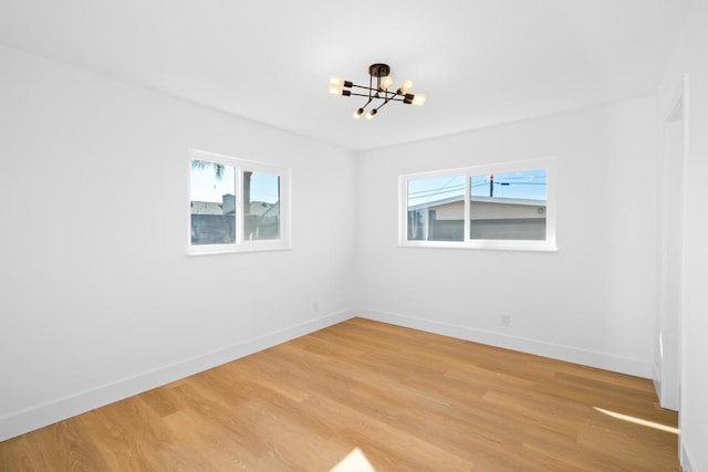 unfurnished room featuring light wood-type flooring and a chandelier