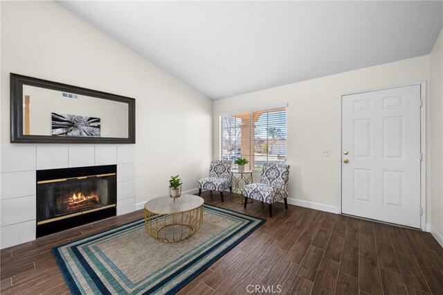 living area with a tile fireplace and lofted ceiling