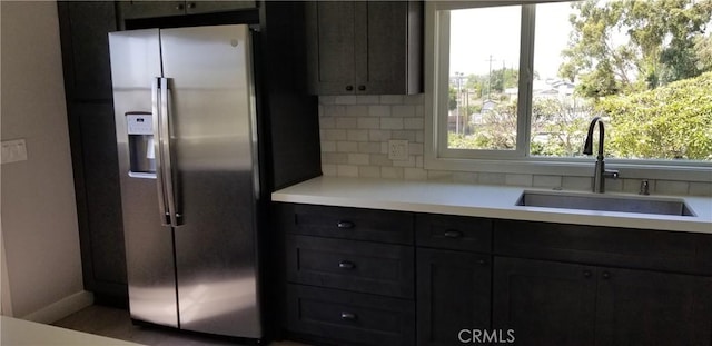 kitchen featuring stainless steel fridge with ice dispenser, backsplash, and sink