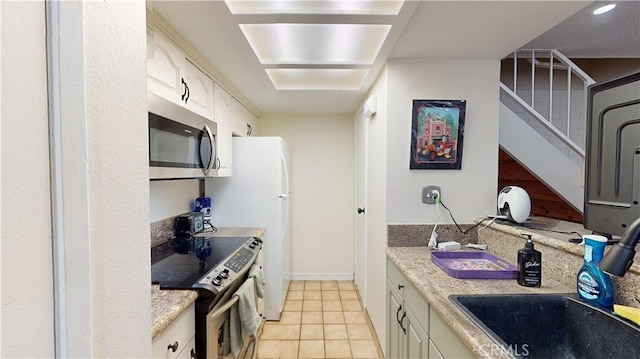 kitchen featuring sink, light tile patterned floors, light stone counters, and appliances with stainless steel finishes