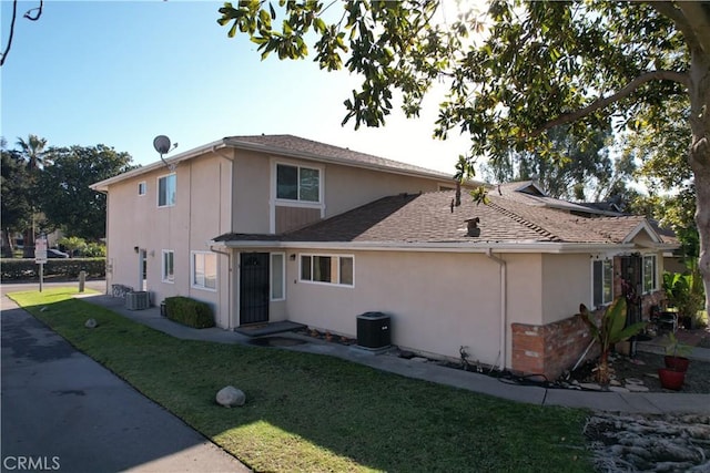 view of front of home with central AC and a front lawn