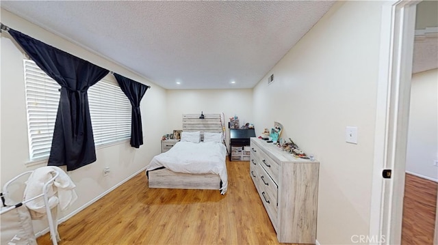 bedroom with light wood-type flooring and a textured ceiling