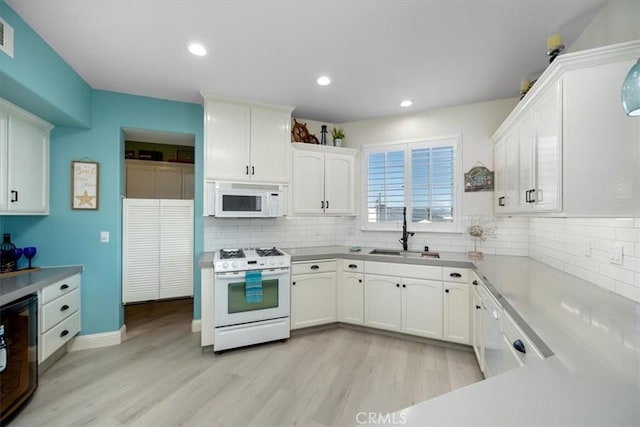 kitchen with tasteful backsplash, white appliances, sink, and white cabinets