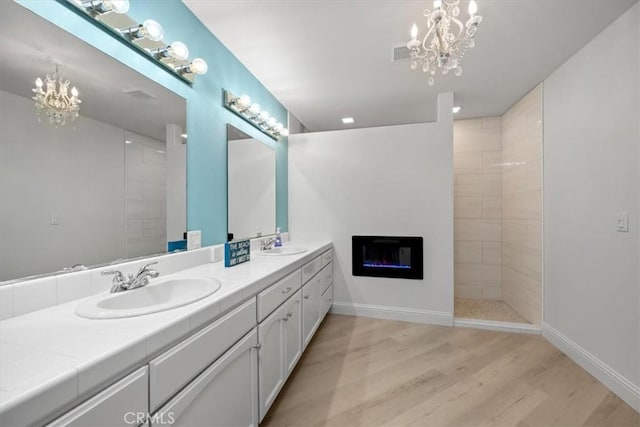 bathroom with vanity, wood-type flooring, a chandelier, and tiled shower