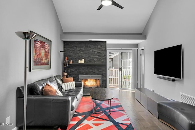 living room with wood-type flooring, a fireplace, ceiling fan, and vaulted ceiling