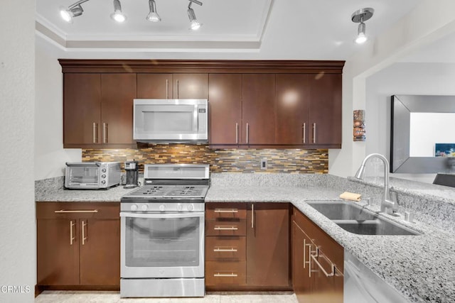 kitchen with stainless steel appliances, decorative backsplash, sink, and light stone countertops