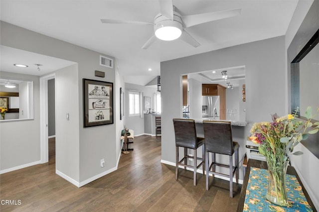 kitchen with dark hardwood / wood-style floors, stainless steel fridge with ice dispenser, a breakfast bar, lofted ceiling, and ceiling fan