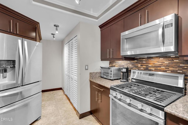 kitchen with light stone countertops, stainless steel appliances, light tile patterned floors, decorative backsplash, and ornamental molding