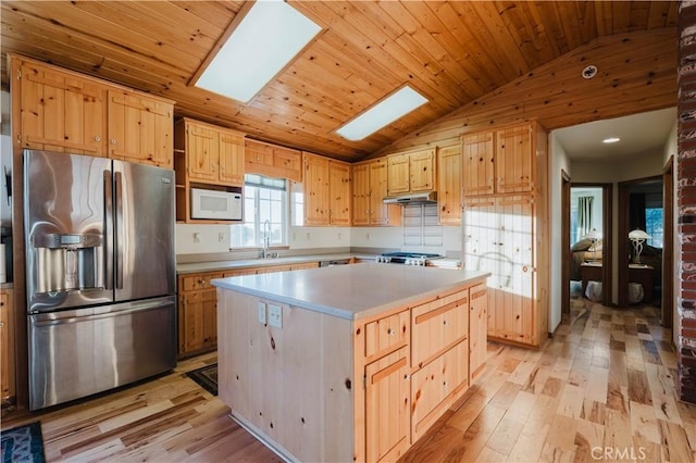 kitchen with light wood finished floors, stainless steel fridge with ice dispenser, white microwave, under cabinet range hood, and lofted ceiling with skylight