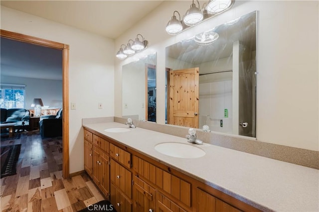 full bathroom featuring double vanity, ensuite bath, a sink, and wood finished floors