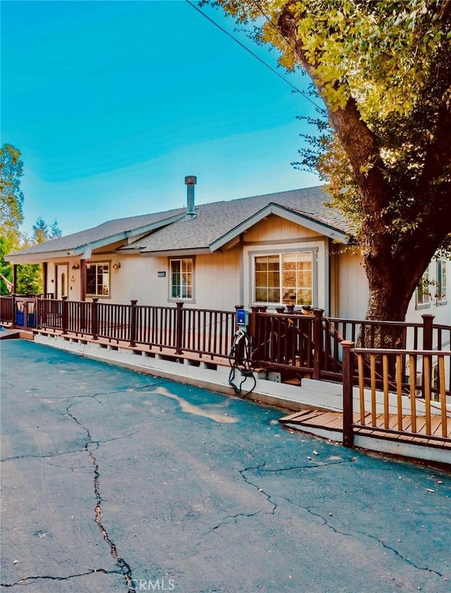 rear view of property with a fenced in pool, a wooden deck, and roof with shingles