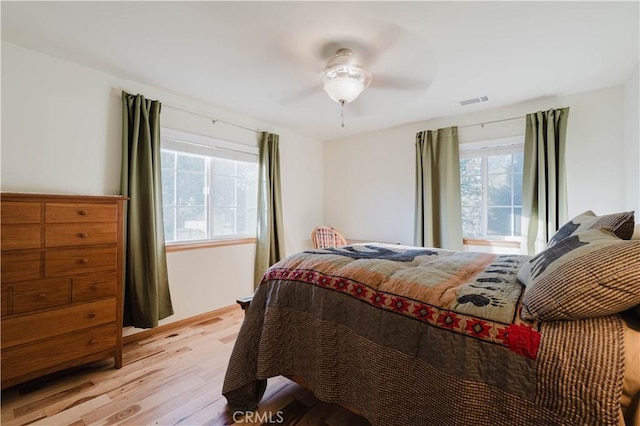 bedroom with a ceiling fan, visible vents, and light wood finished floors