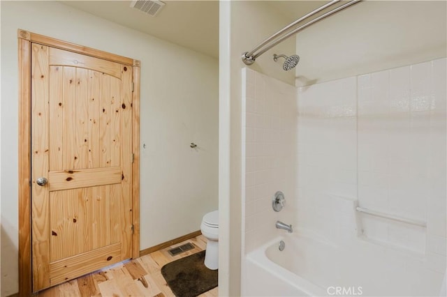 bathroom with toilet, hardwood / wood-style flooring, and shower / washtub combination