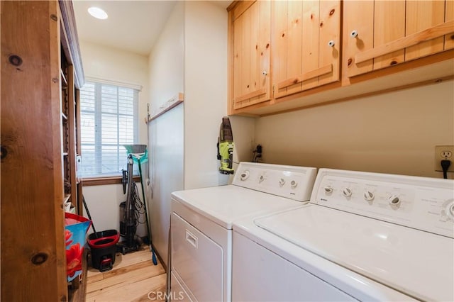 washroom with washer and dryer, light wood-type flooring, and cabinet space